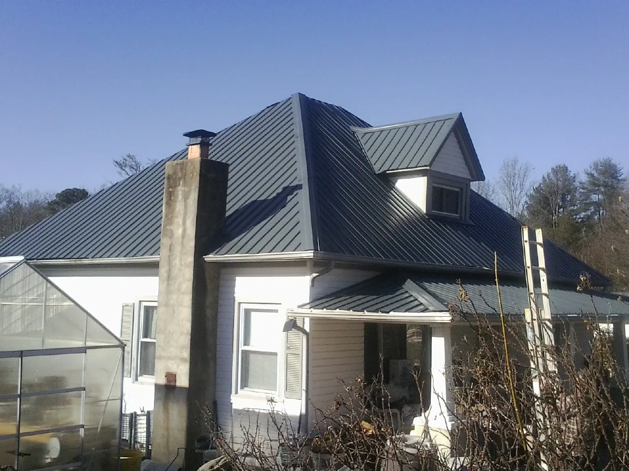 Dark blue standing seam metal roof on a white farmhouse with dormer — Slate & Tile Roof Repair by Roofing Brothers in Browerville