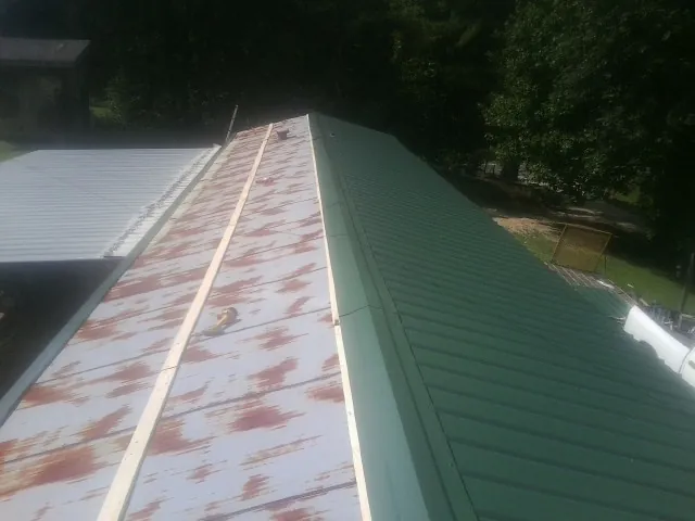 Old rusted panels beside newly installed green metal roofing — Wind Damage Roof Repair by Roofing Brothers in Browerville