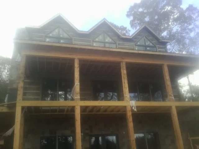 Dormers and porch framing on a large log home under construction — Roof Coating work by our crew in Browerville