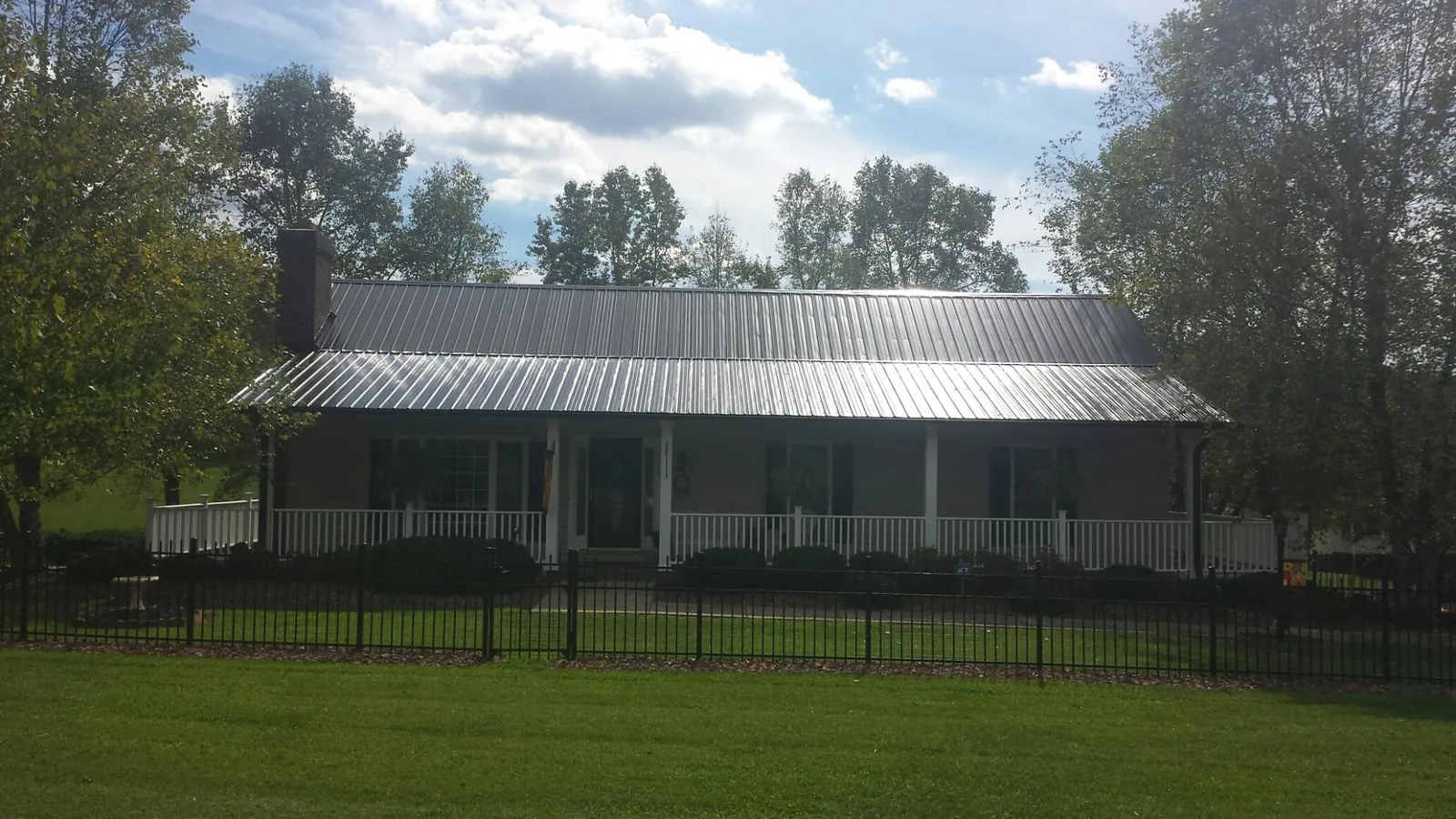 Gray metal roof on a brick ranch with a full width front porch — Gutter Guard Installation work by our crew in Browerville