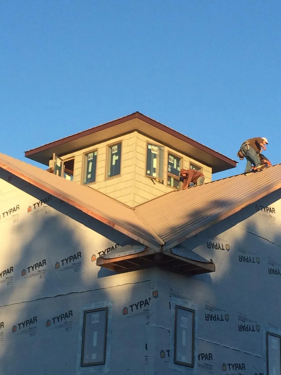 Roofers working around a rooftop cupola on a new metal roof at sunset — Roof Waterproofing in Browerville by Roofing Brothers
